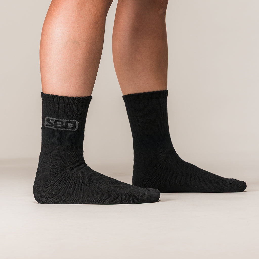 Black SBD Crew Socks with grey logos, side view on an athlete