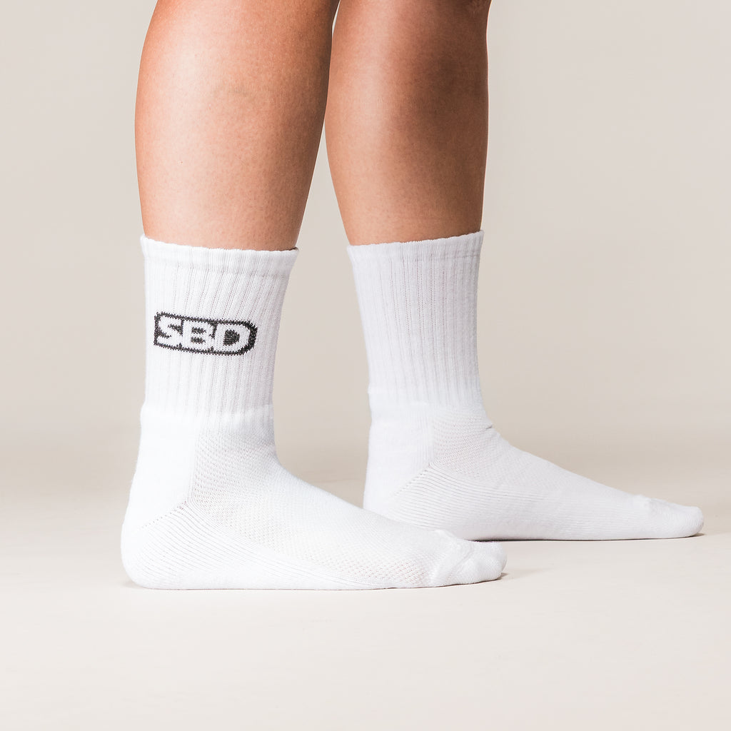 White SBD Crew Socks with black logos, side view on an athlete