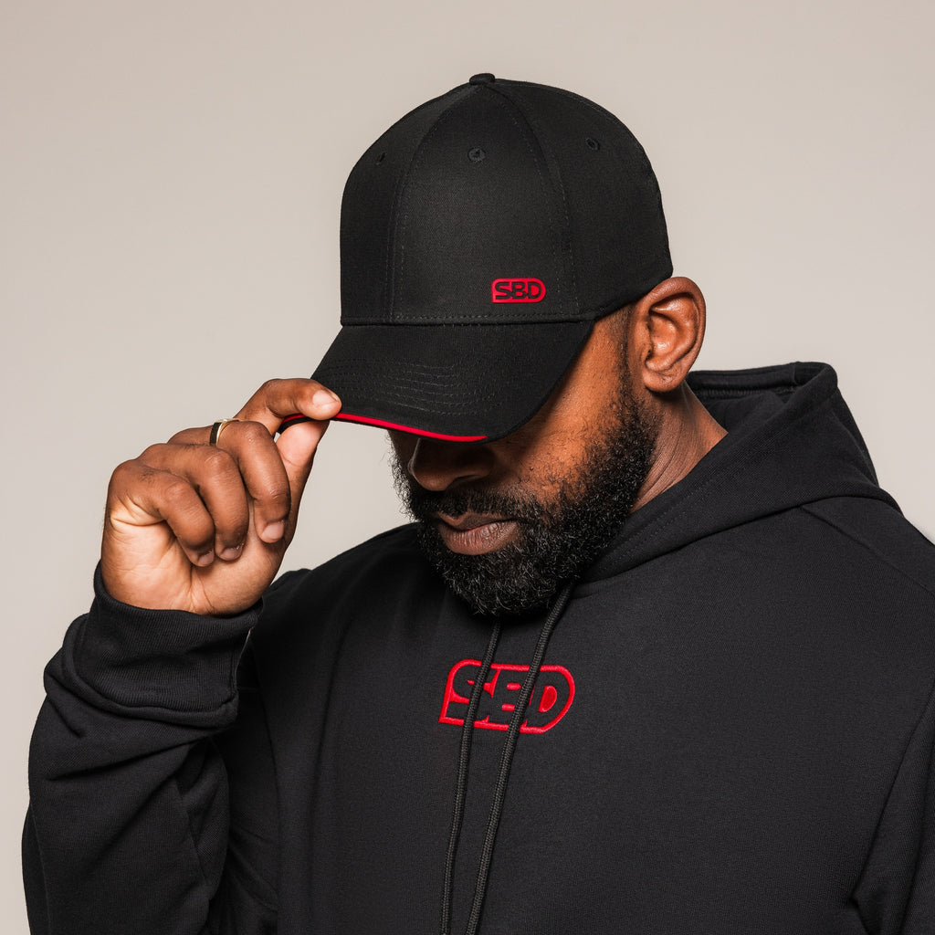 Black SBD Cap with red logo and brim trim, worn by an athlete