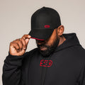 Black SBD Cap with red logo and brim trim, worn by an athlete