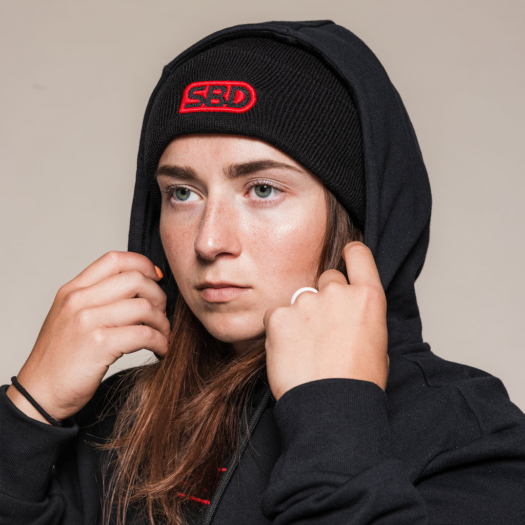 Black SBD Beanie worn under a raised hoodie