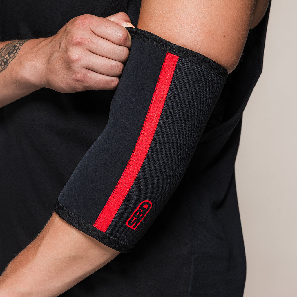 Black and red SBD Elbow Sleeve, close-up of the upper edge being adjusted