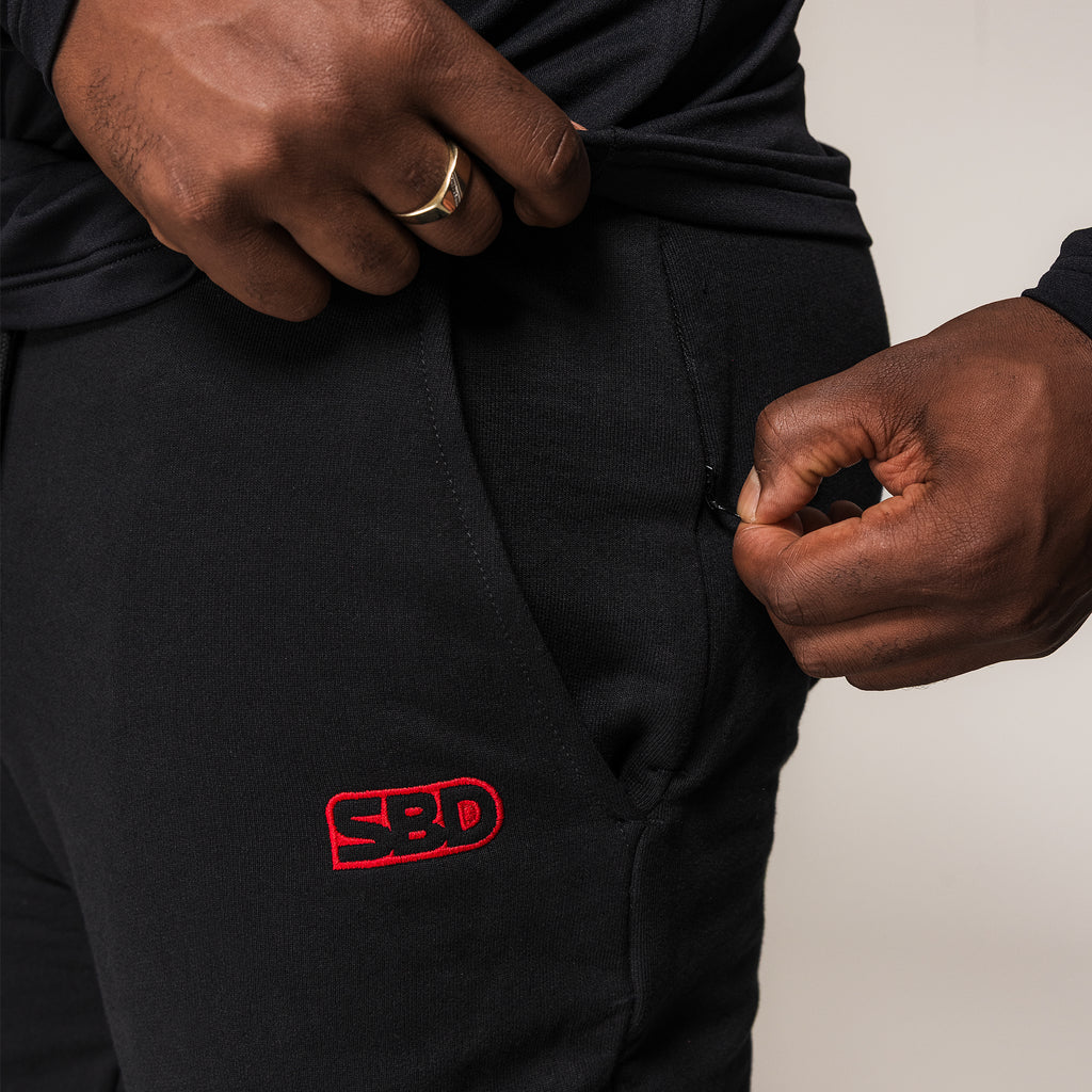 Black SBD Joggers, close-up of the zipped pocket and red embroidered logo