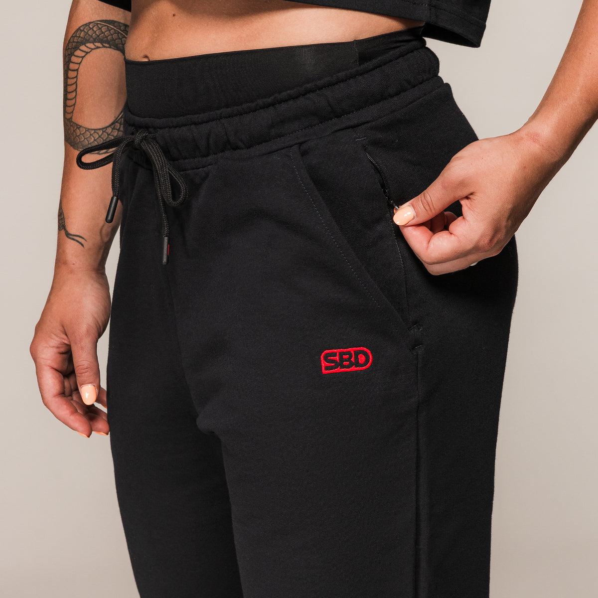 Black SBD Joggers, close-up of the red embroidered logo and pocket