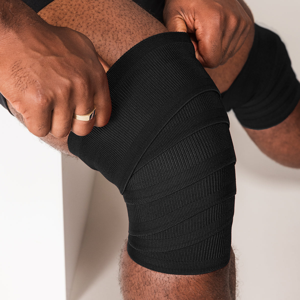 Black SBD Competition Knee Wrap being tightened around the knee