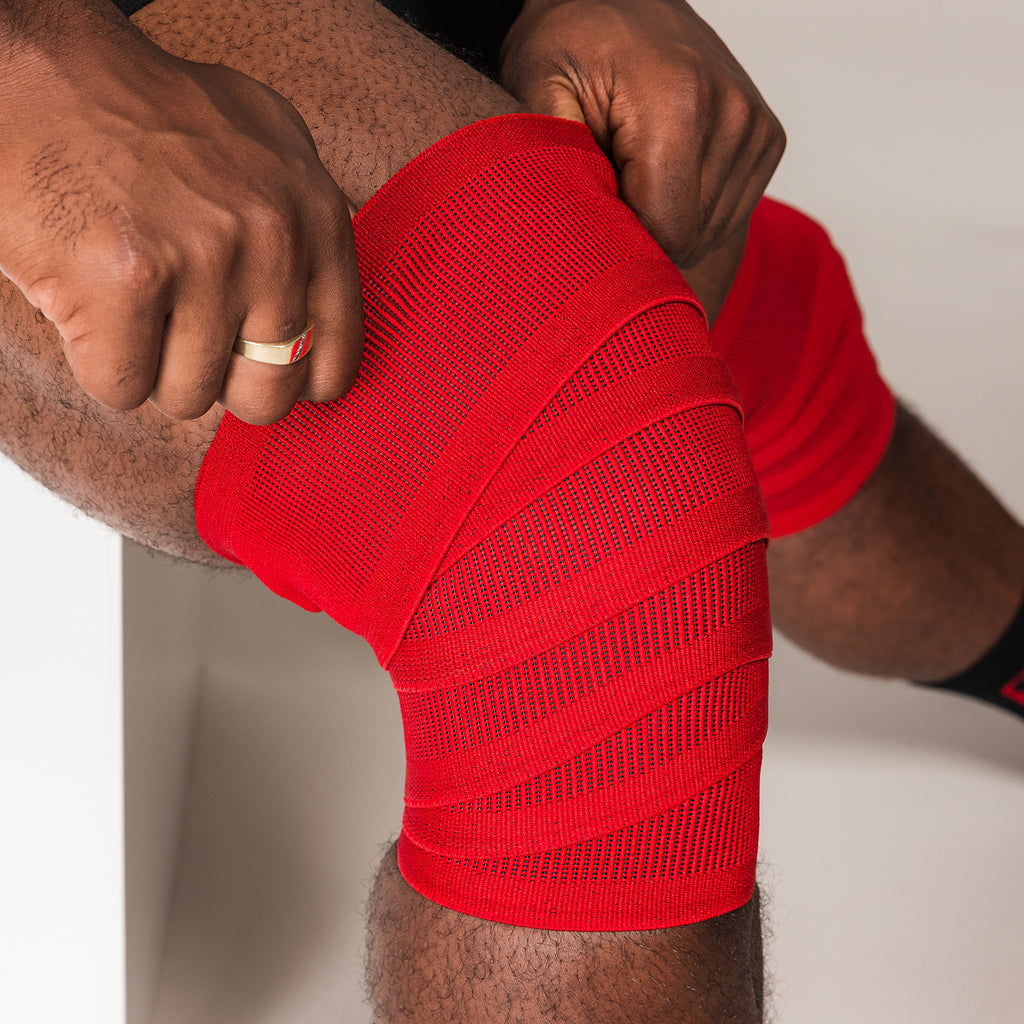 Red SBD Training Knee Wrap being tightened around the knee