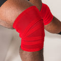 Red SBD Training Knee Wrap secured around a bent knee