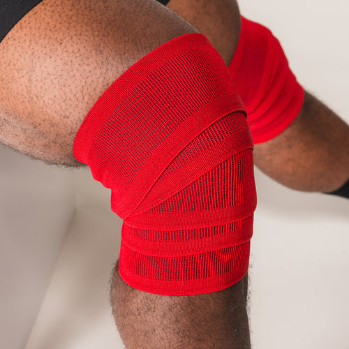 Red SBD Training Knee Wrap secured around a bent knee