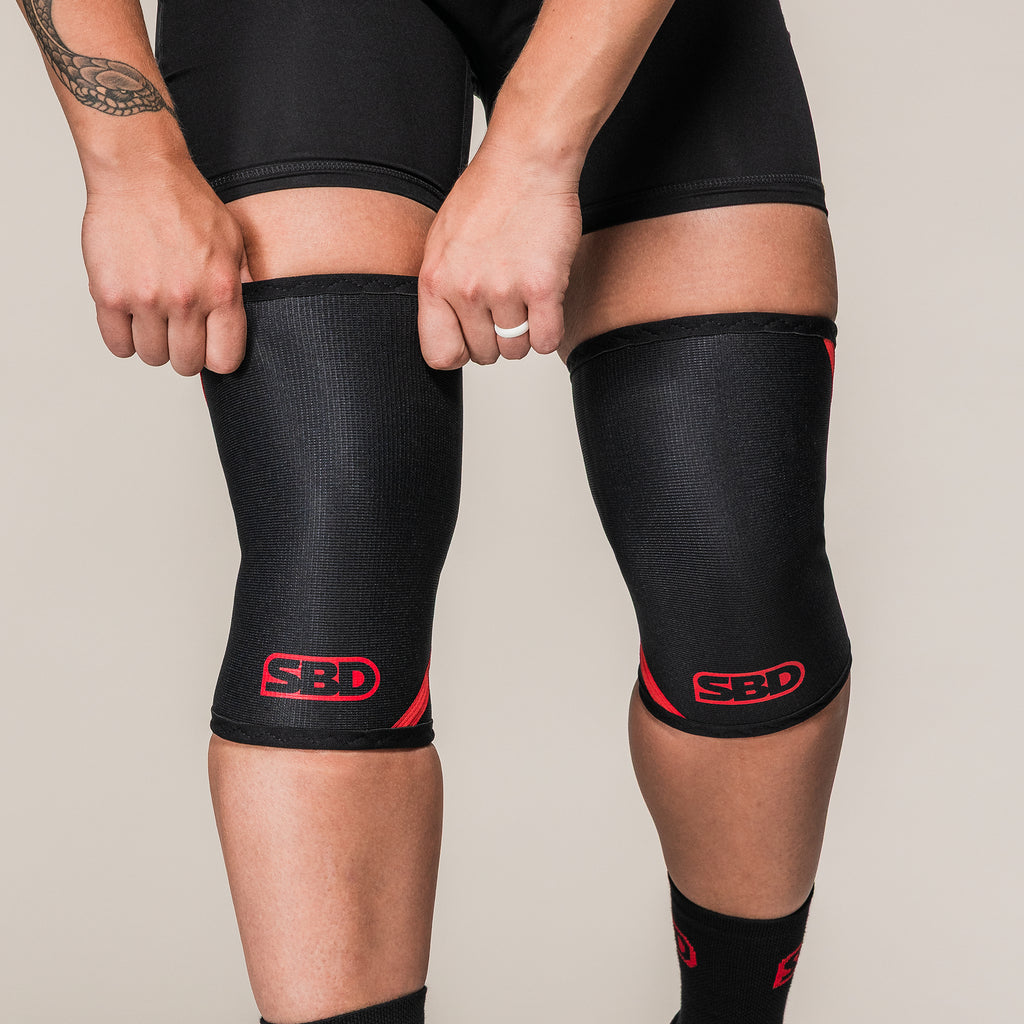 Black and red SBD Weightlifting Knee Sleeves, front view on an athlete