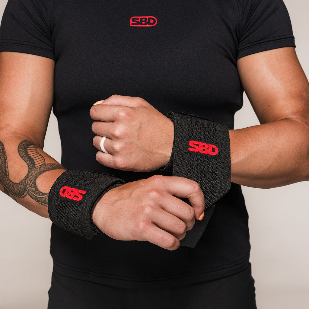 Black and red SBD Flexible Wrist Wraps, front view on an athlete