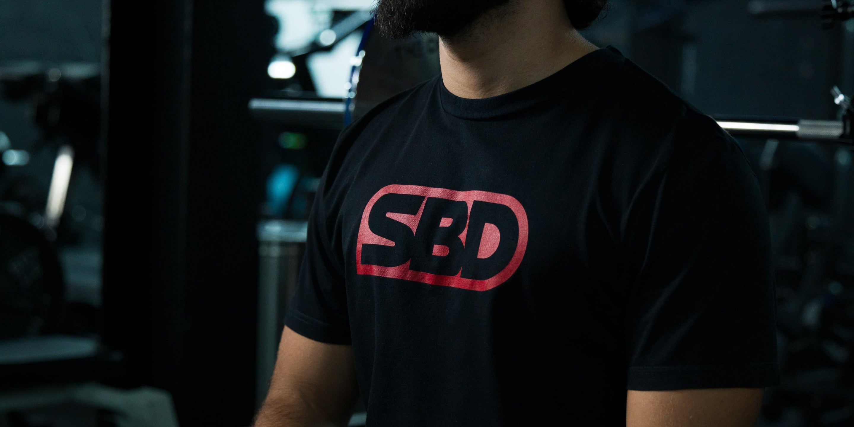 Person wearing a classic SBD brand t-shirt in a dark setting